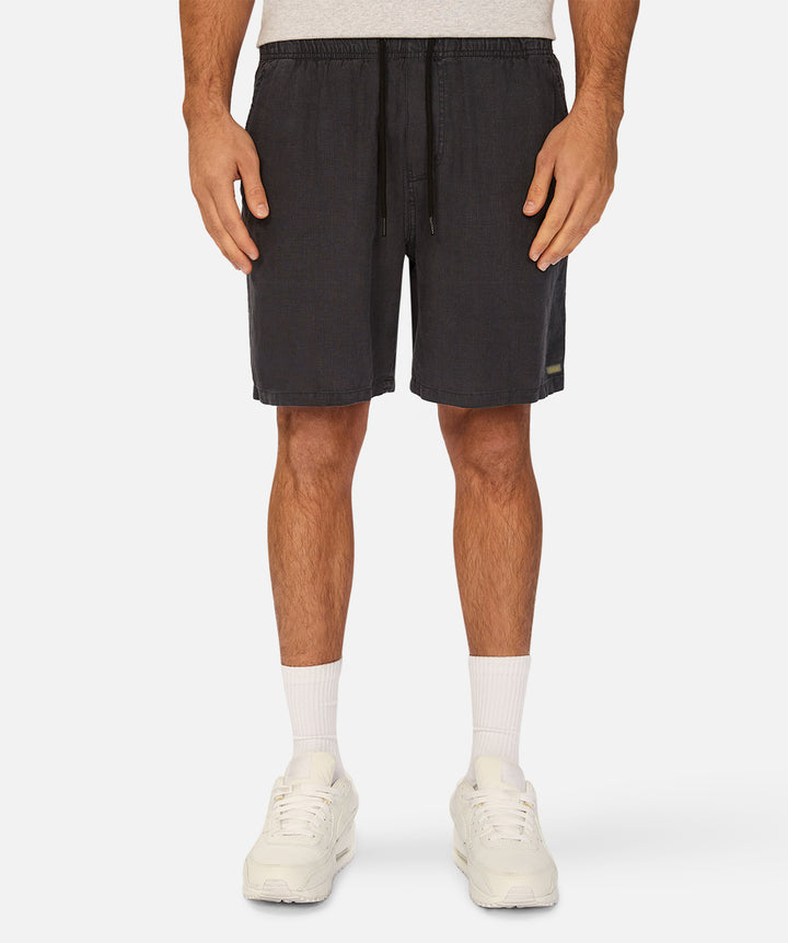 A person wearing dark charcoal drawstring shorts, white crew socks, and white sneakers, shown from the waist down against a light gray studio background.