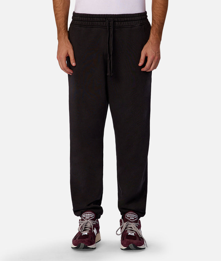 Person wearing black jogger pants with a white background
