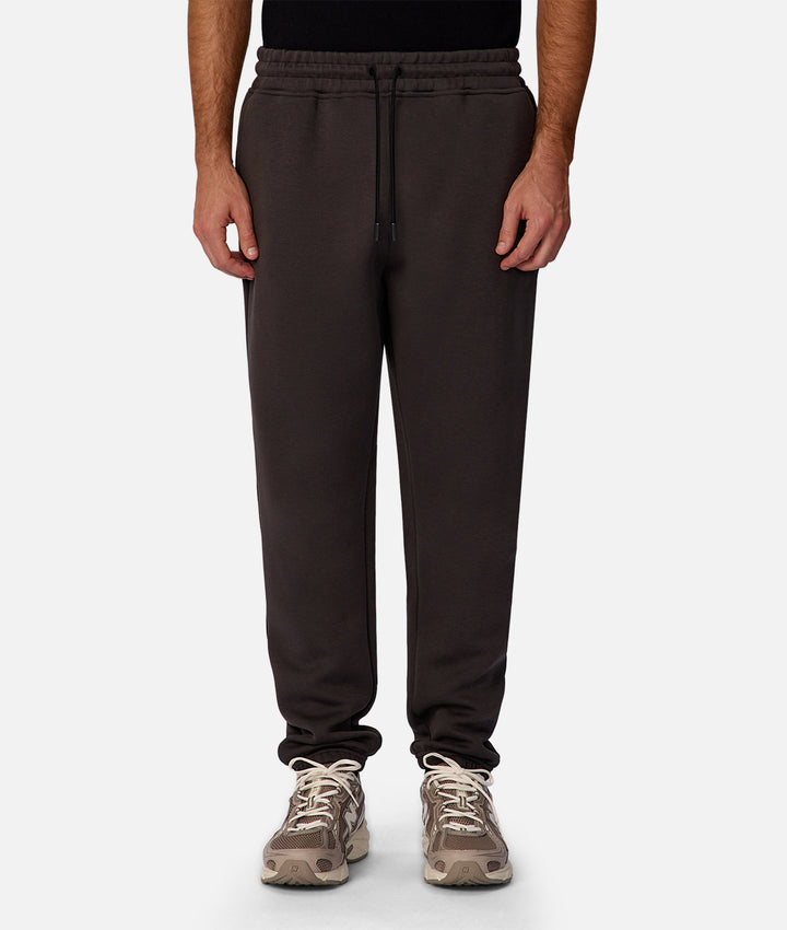 Person wearing dark brown sweatpants on a white background