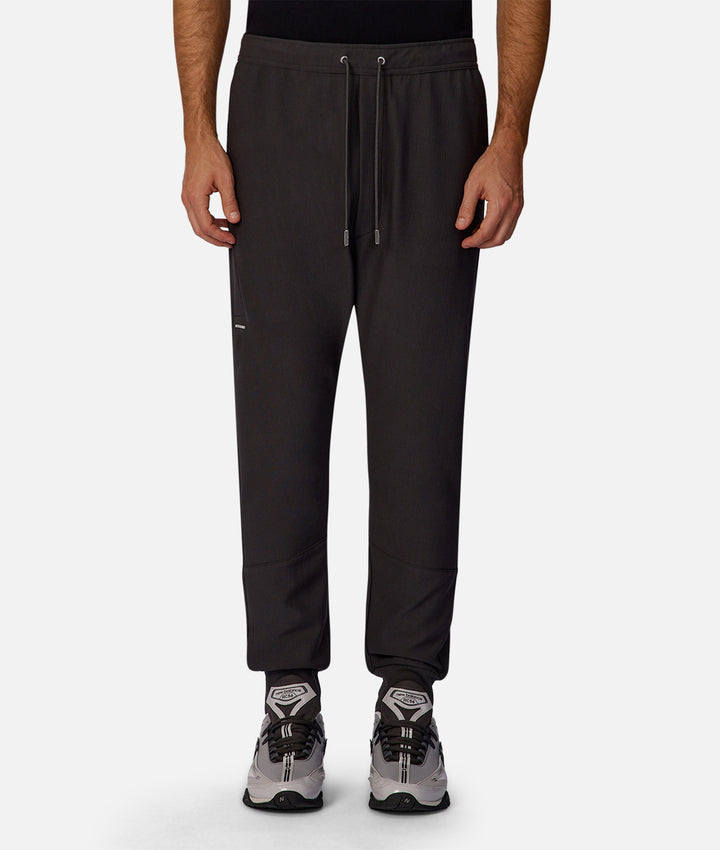 Person wearing black jogger pants on a white background