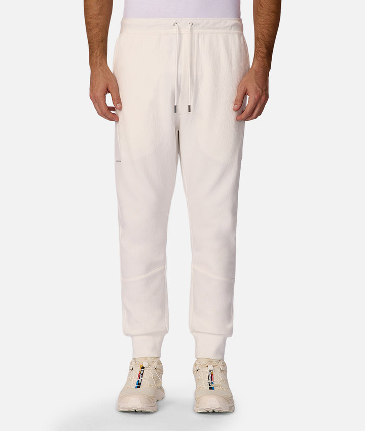 White sweatpants worn by a person on a white background