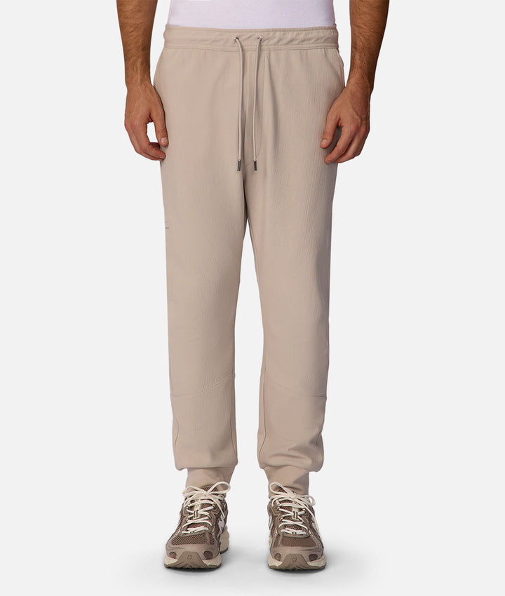 Beige sweatpants worn by a person on a white background