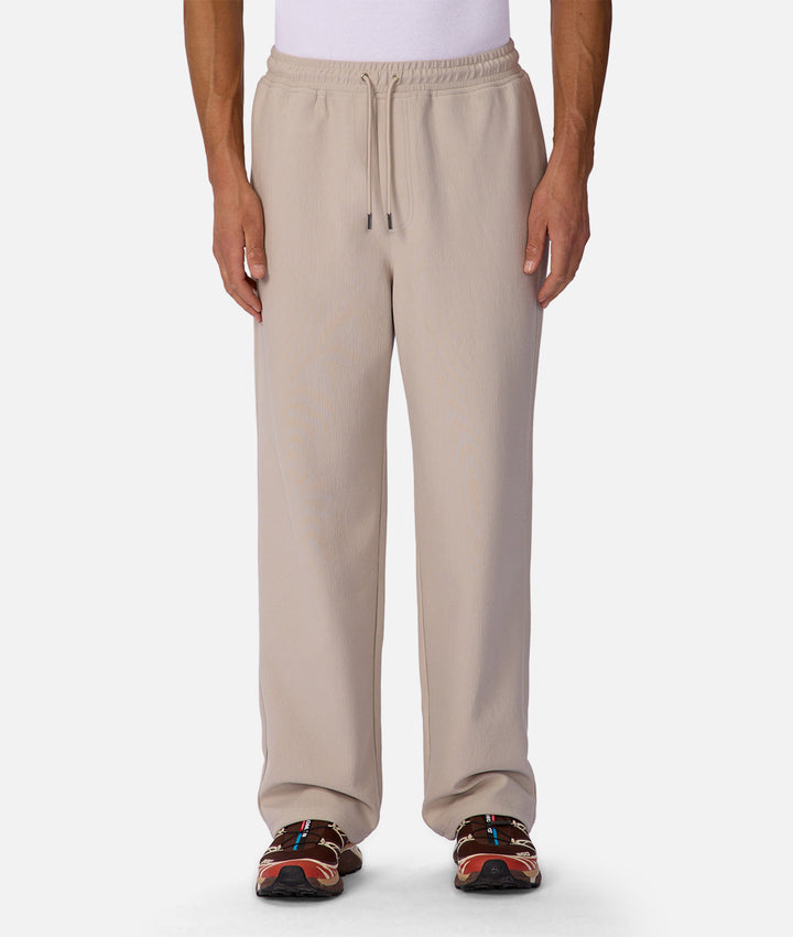 Beige sweatpants worn by a person on a white background