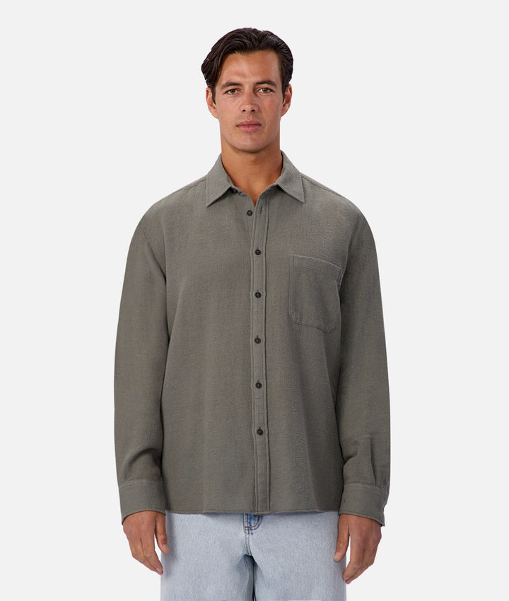 Man wearing a gray button-up shirt on a white background