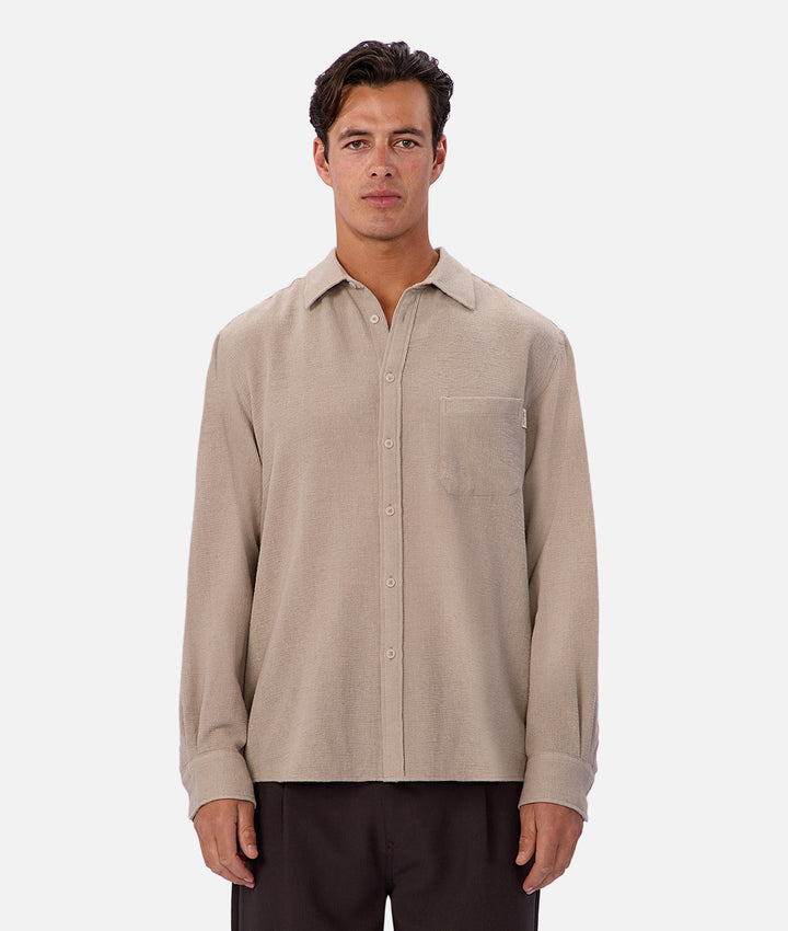 Man wearing a beige button-up shirt on a white background
