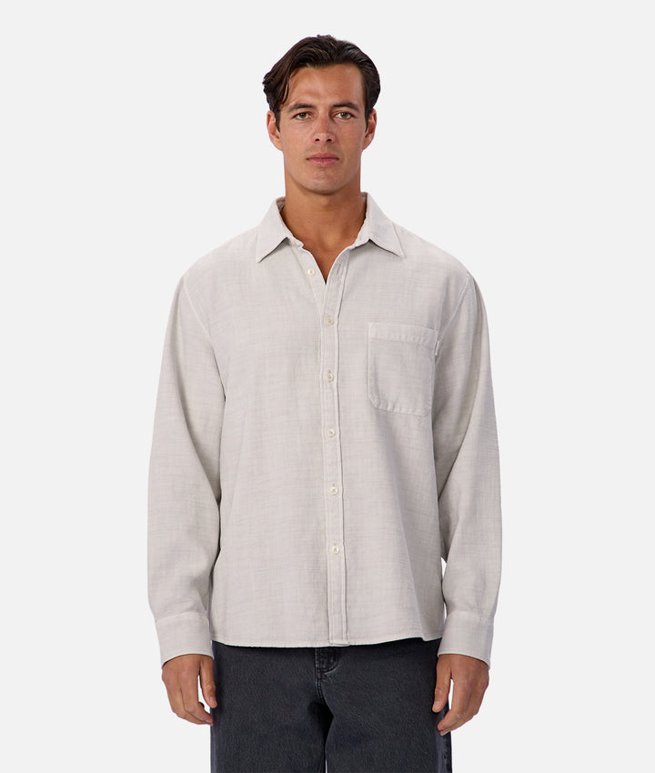 Man wearing a light gray button-up shirt against a white background