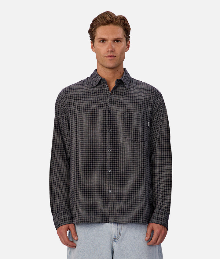 Man wearing a black and gray checkered shirt on a white background