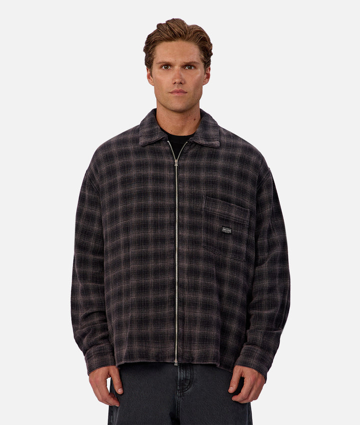 Man wearing a plaid shirt with a visible brand logo on a white background