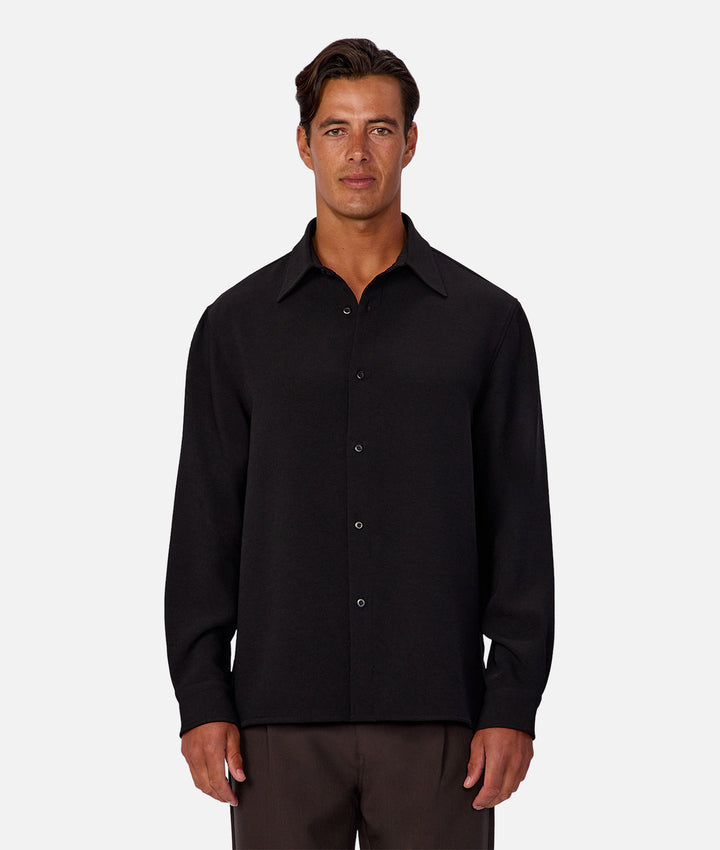 Man wearing a black button-up shirt against a white background