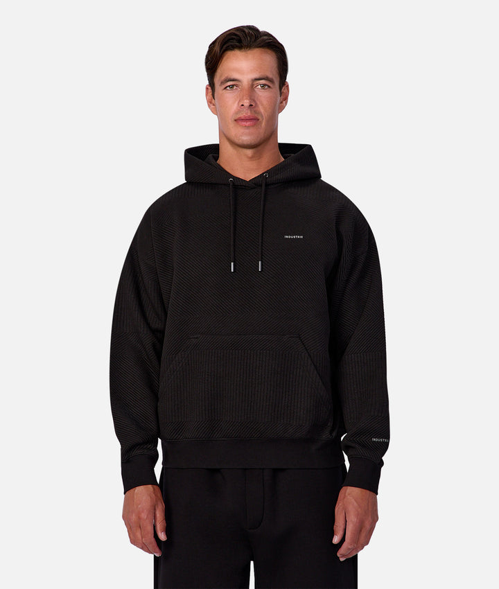 Man wearing a black hoodie with a brand logo on a white background
