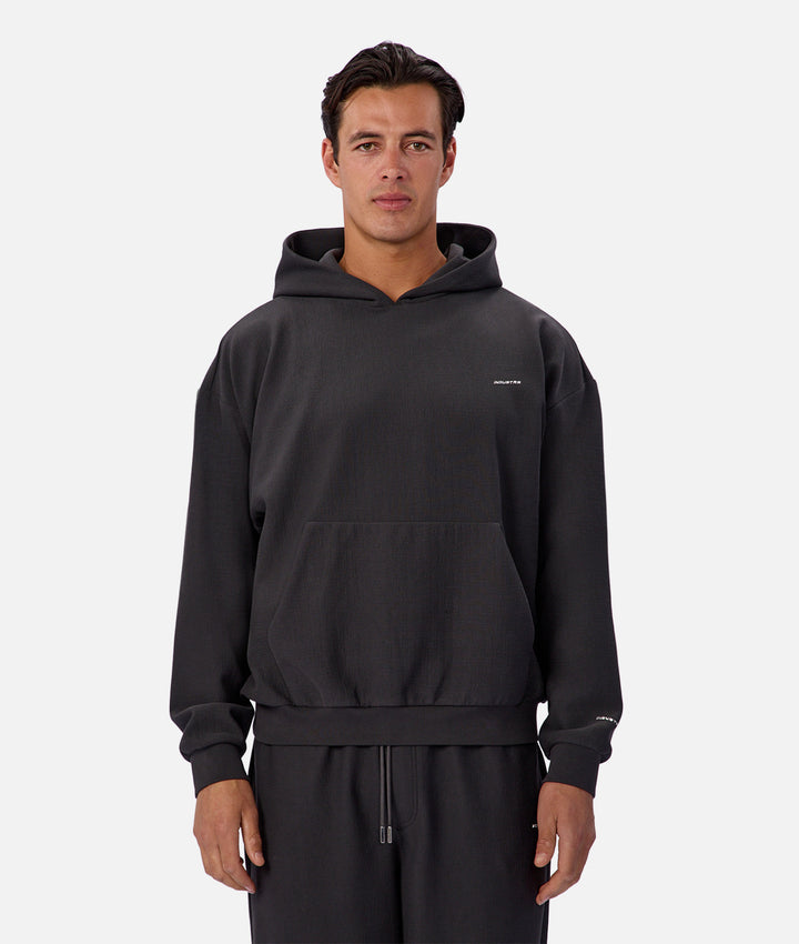 Man wearing a black hoodie with a brand logo on a white background