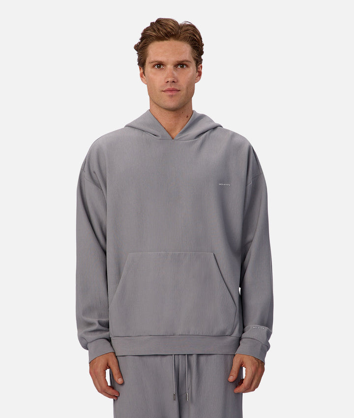 Man wearing a gray hoodie and pants on a white background