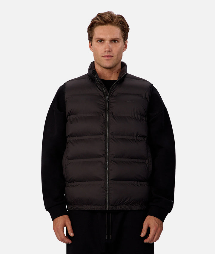 Man wearing a black puffer vest on a white background
