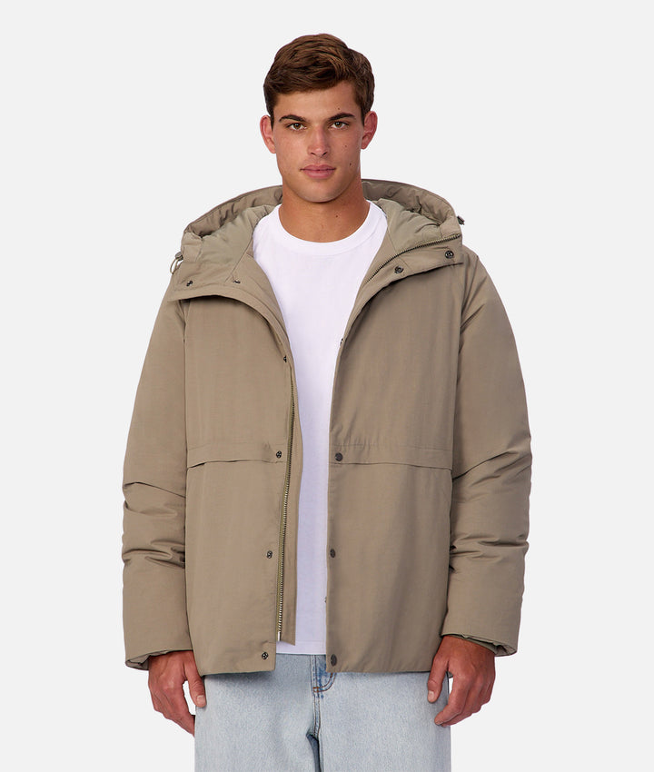 Man wearing a beige hooded jacket on a white background