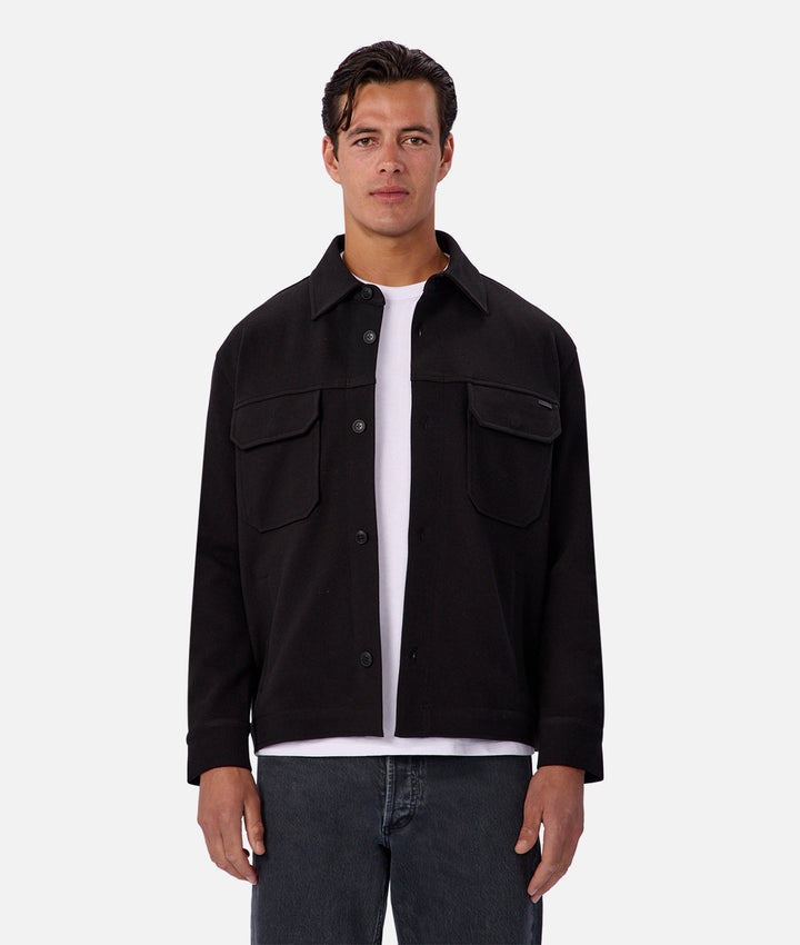 Man wearing a black jacket over a white shirt on a white background
