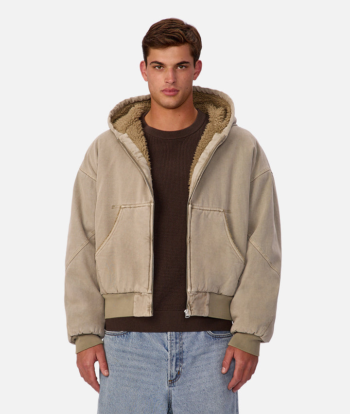 Man wearing a beige jacket with a sherpa lined hood on a white background