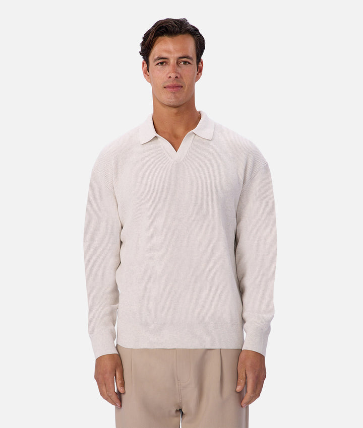 Man wearing a light-colored sweater over a white shirt on a white background