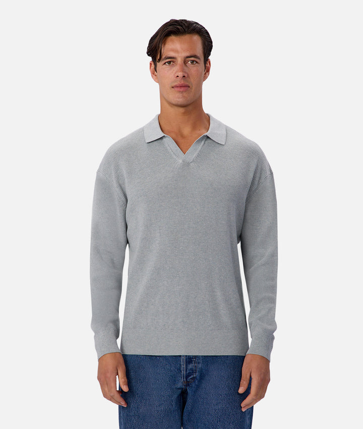 Man wearing a gray sweater over a collared shirt on a white background