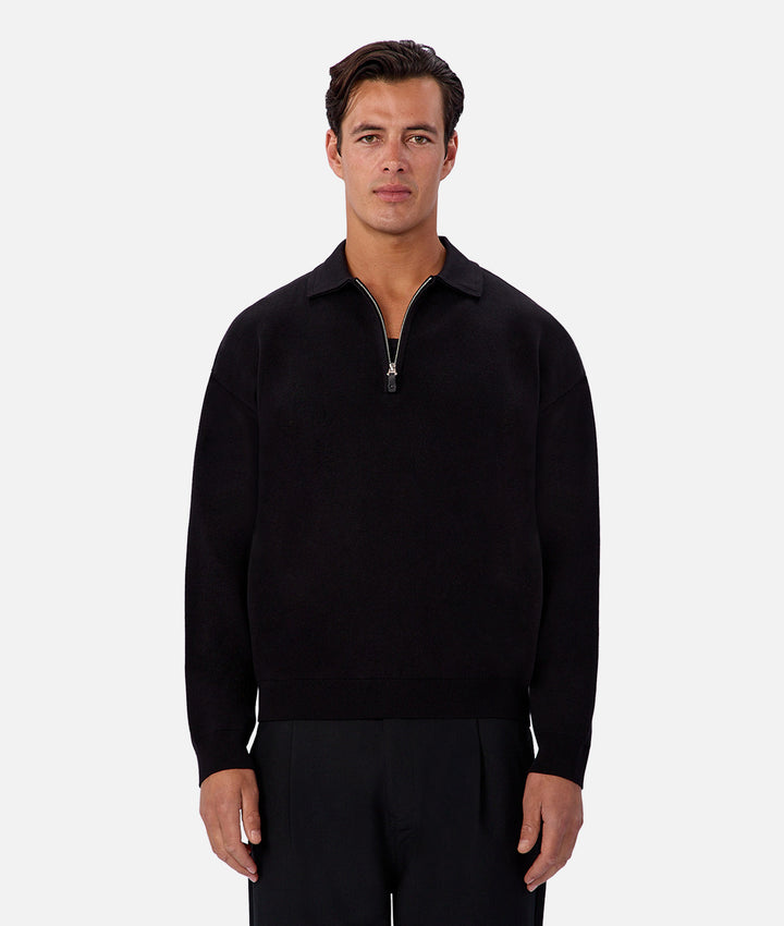 Man wearing a black quarter-zip sweater on a white background