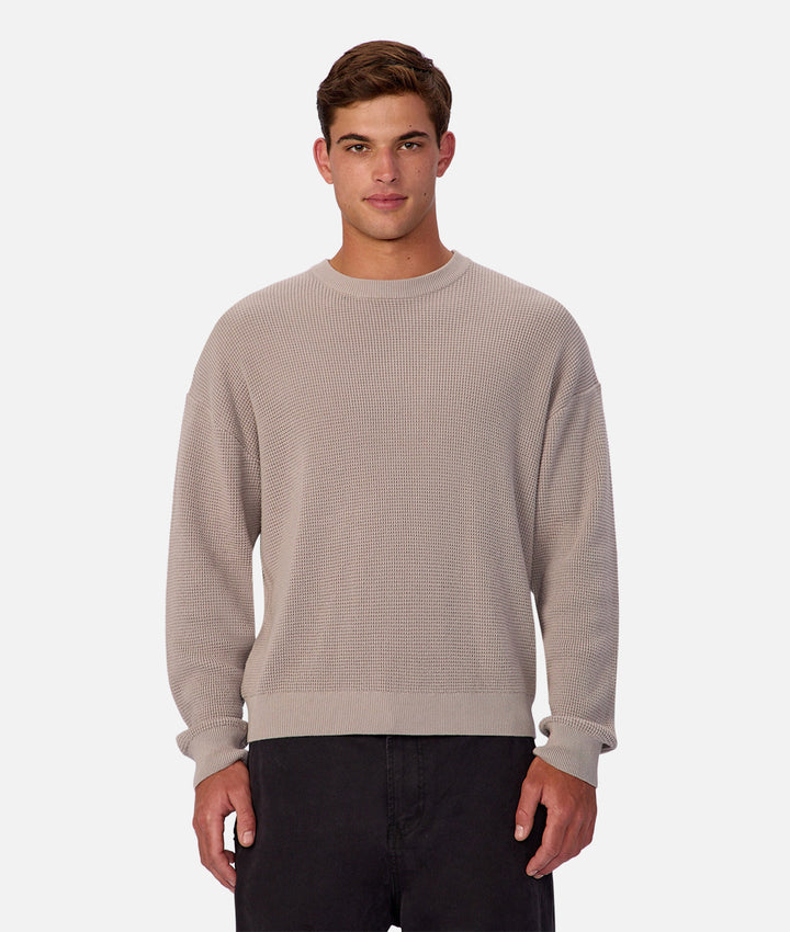 Man wearing a beige textured sweater on a white background