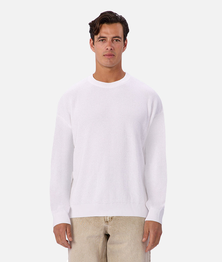 Man wearing a white sweater on a plain background