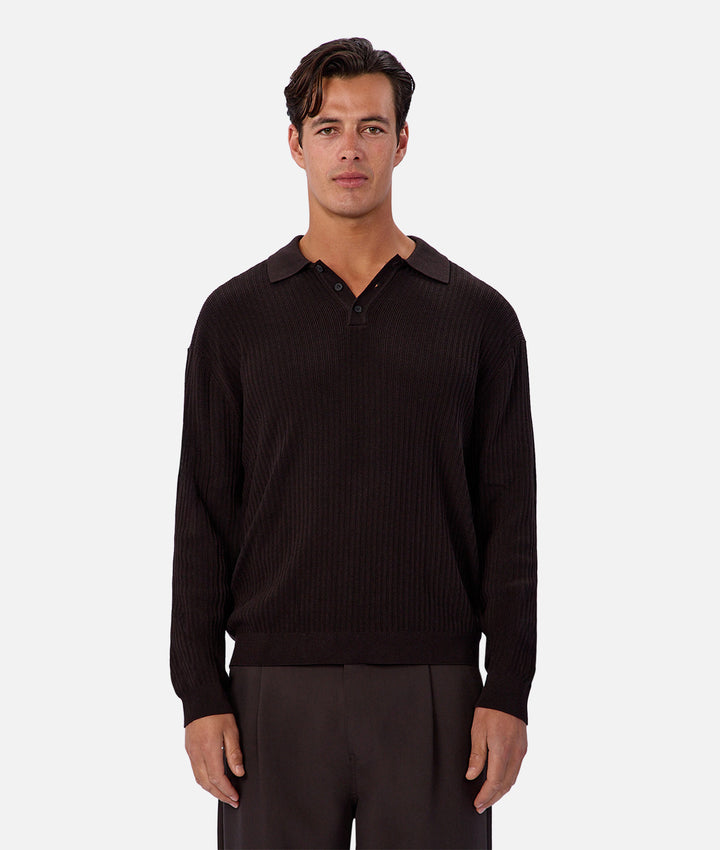 Man wearing a dark brown ribbed sweater and pants on a white background