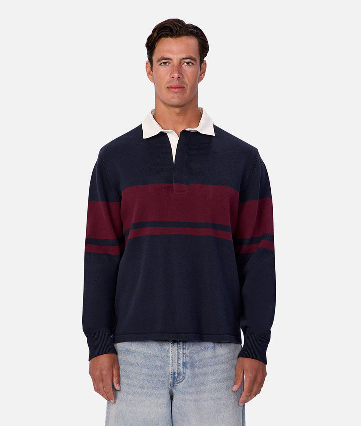 Man wearing a navy and red striped rugby shirt on a white background