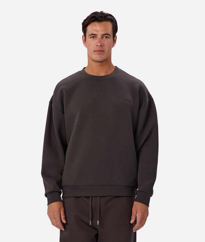 Man wearing a dark brown sweatshirt and pants on a white background