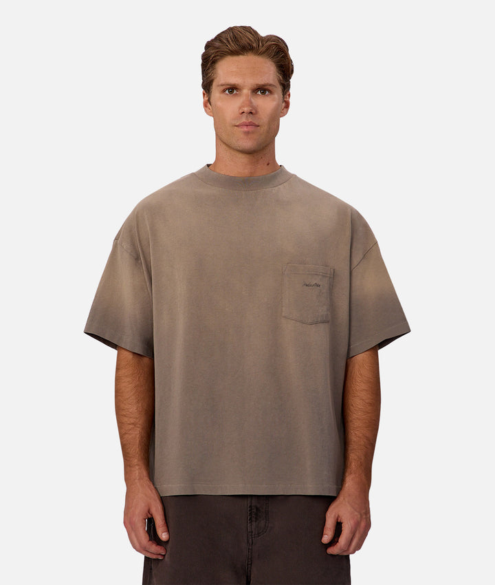 Man wearing a brown t-shirt with a pocket on a white background