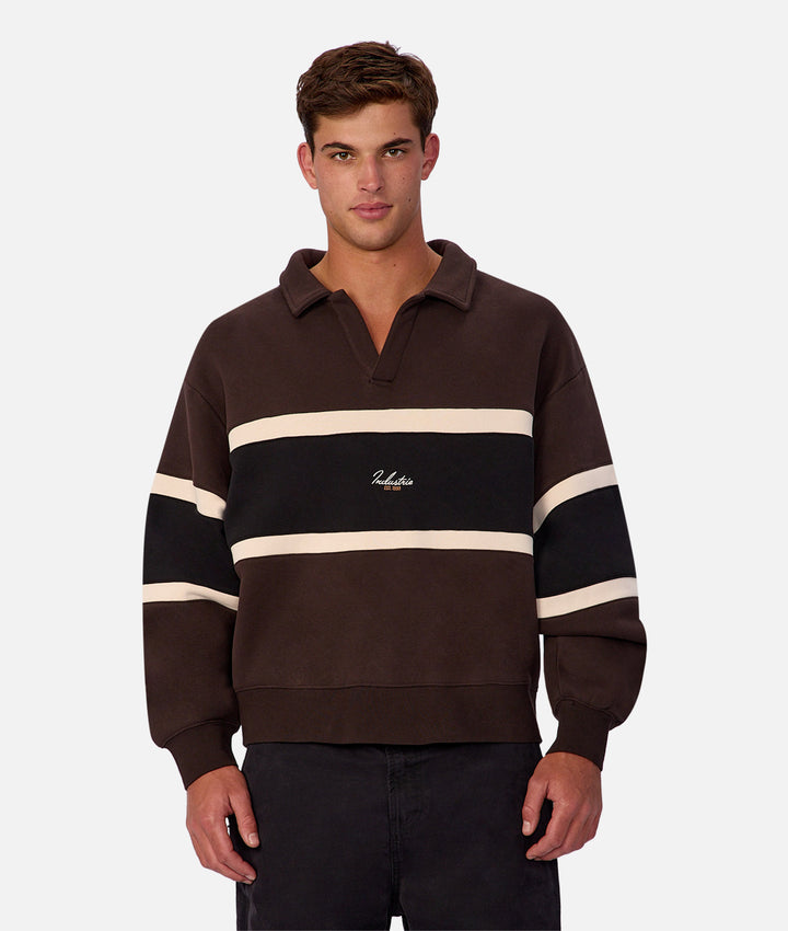 Man wearing a brown and black striped sweater with a visible brand logo on a white background
