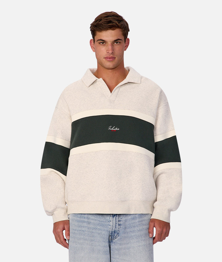 Man wearing a cream and black striped sweater with a logo on a white background