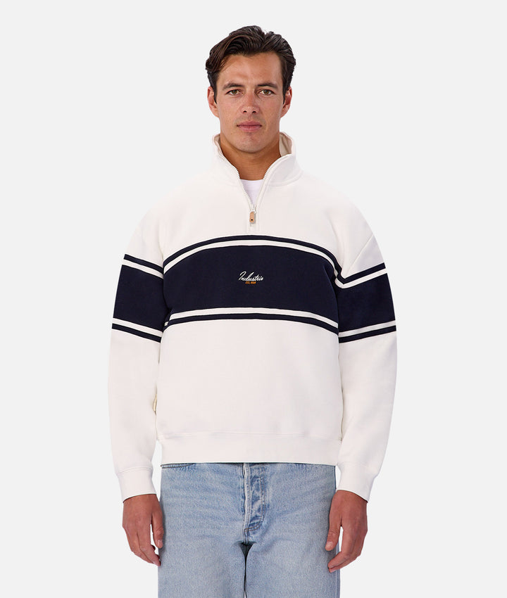 Man wearing a white and navy striped sweater with a logo on a white background