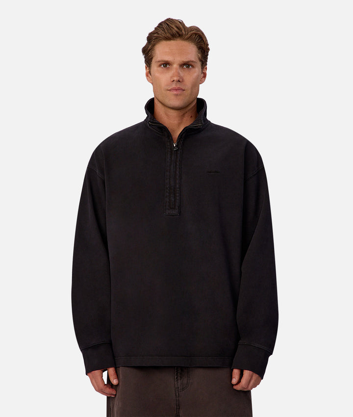 Man wearing a black pullover with a quarter zip on a white background