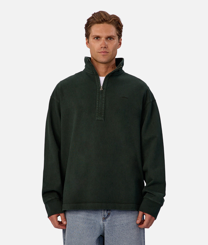 Man wearing a dark green pullover with a quarter-zip design on a white background