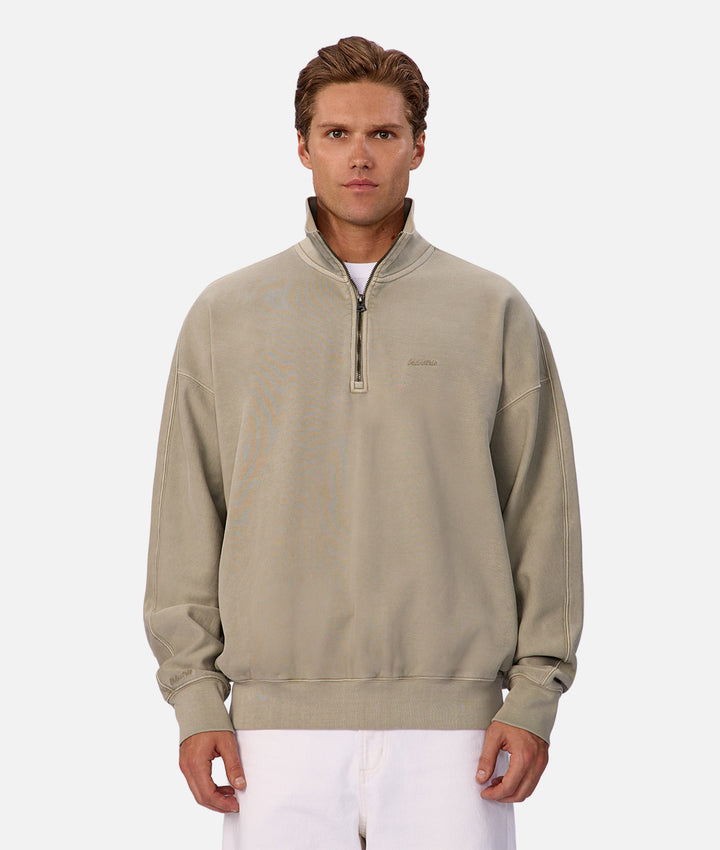 Man wearing a beige half-zip sweatshirt on a white background