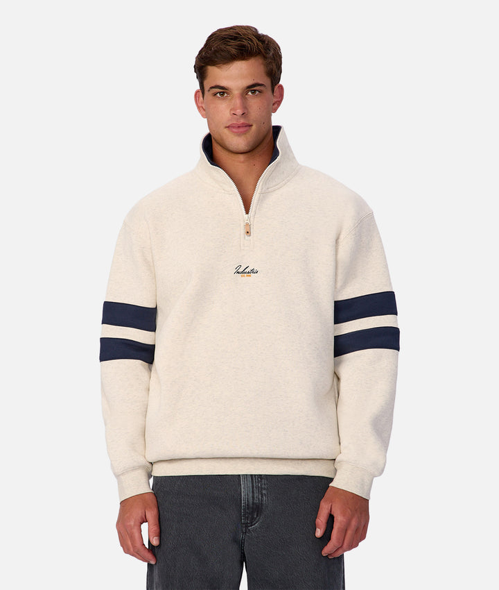 Man wearing a cream-colored sweater with navy stripes on a white background